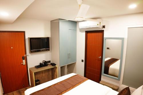 a hotel room with a bed and a tv and a bedroom at Dream Hotel - Richmond in Bangalore