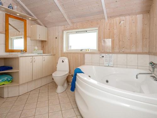 a bathroom with a tub and a toilet and a sink at 7 person holiday home in Harbo re in Harboør