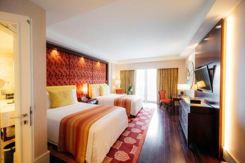 a hotel room with two beds and a television at The Ritz-Carlton, Bangalore in Bengaluru