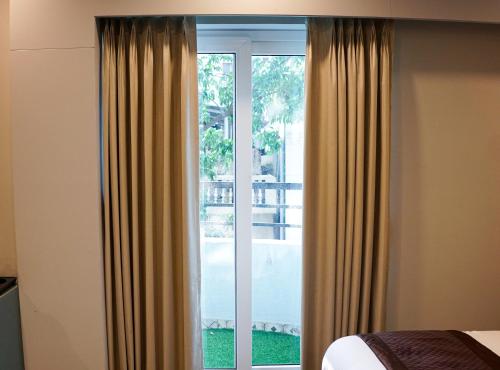 a bedroom with a large window with curtains at Dream Hotel - Richmond in Bengaluru