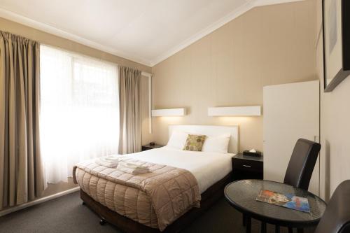 a hotel room with a bed and a table and a window at Mittagong Motel in Mittagong