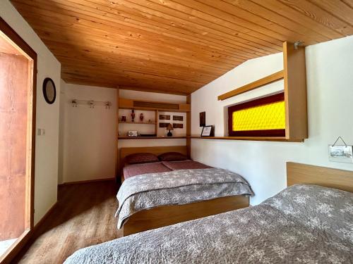 two beds in a room with a wooden ceiling at Family lake house Zbilje in Ljubljana