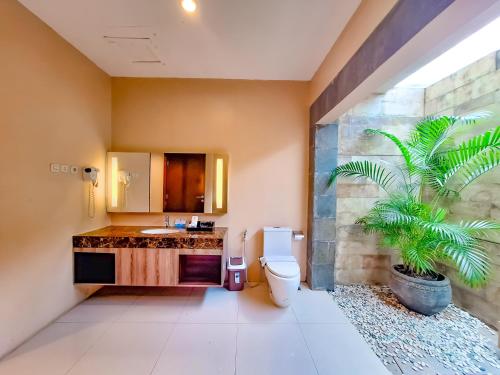 a bathroom with a sink and a toilet and a plant at Sekuro Village Beach Resort in Jepara