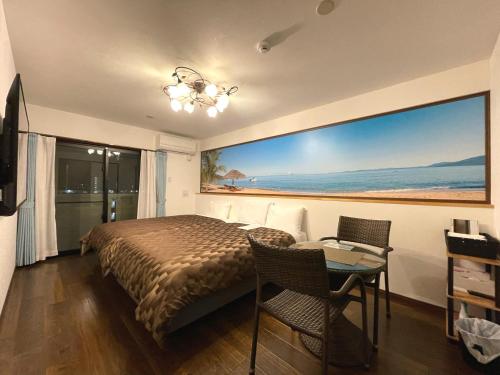 a bedroom with a bed and a table and a large window at Ao Hotel in Nago