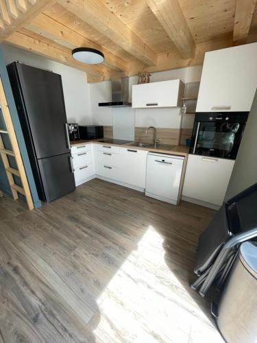 une cuisine avec des armoires blanches et un réfrigérateur noir dans l'établissement La Caravelle, à Saint-Gilles-Croix-de-Vie