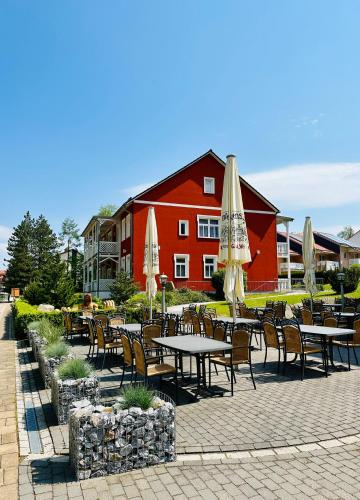 a group of tables and chairs with umbrellas in front of a building at Hotelpark Bodetal mit Ferienwohnungen in Thale
