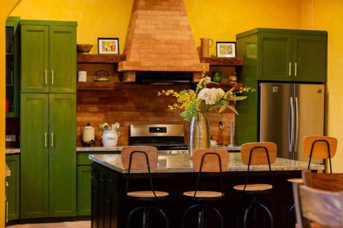 a kitchen with green cabinets and a counter with chairs at The Palm- A Luxury Villa in Retalhuleu