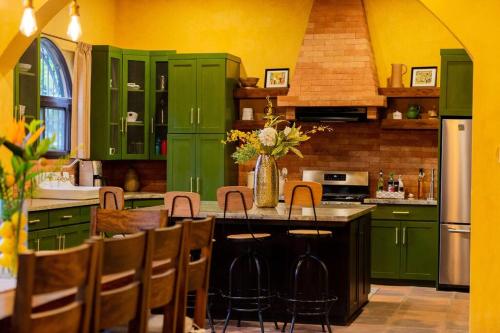 a kitchen with green cabinets and a table with chairs at The Palm- A Luxury Villa in Retalhuleu