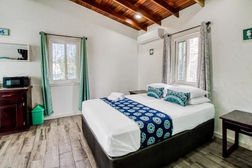 a bedroom with a bed and a desk and two windows at DV 3 at DV Cabanas Gold Standard Certified in Caye Caulker