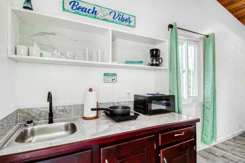 a kitchen with a sink and a microwave at DV 3 at DV Cabanas Gold Standard Certified in Caye Caulker