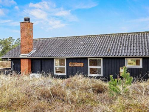 ブラーバンドにある6 person holiday home in Bl vandの野地の煉瓦煙突のある黒家