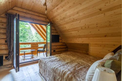a bedroom in a log cabin with a bed and a window at Casa Montana in Kopaonik
