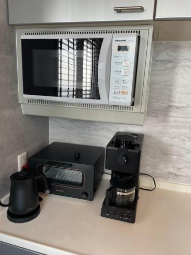 a kitchen counter with a coffee maker and a microwave at 葉山THE TERRACE HOUSE in Hayama