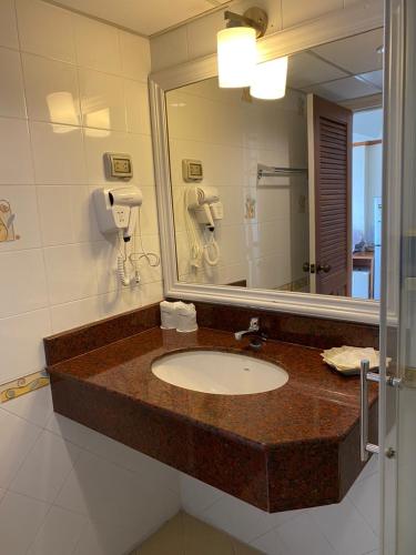 a bathroom with a sink and a mirror at Seaview Sriracha Hotel in Si Racha