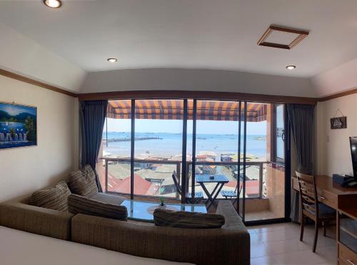 a living room with a couch and a large window at Seaview Sriracha Hotel in Si Racha