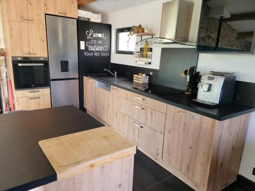 eine Küche mit Holzschränken und einer schwarzen Arbeitsplatte in der Unterkunft Chaleureuse bergerie rénovée. in Tourrette-Levens