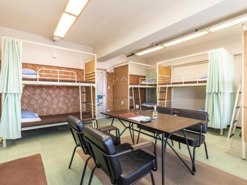 a room with a table and chairs and bunk beds at Omotenashi Hostel Miyajima in Hatsukaichi