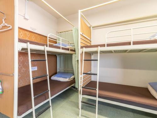 a room with bunk beds in a dorm room at Omotenashi Hostel Miyajima in Hatsukaichi