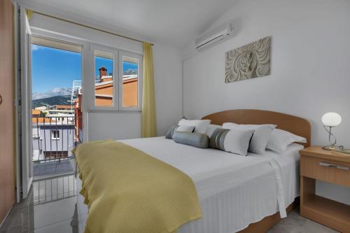 a white bedroom with a bed and a balcony at Ana Apartment in Makarska