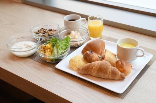 a table with a plate of bread and cups of coffee at R&B Hotel Ueno Hirokoji in Tokyo