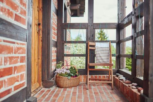 a porch with a chair and a basket of flowers at SPOKÓJ & DOBRO - slow life apartments in Gąski