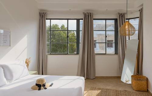 a bedroom with a white bed and large windows at Renovated Historical Roof Top Apt by the Beach in Tel Aviv
