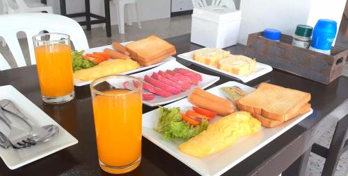 a table with plates of food and two glasses of orange juice at U&D guest house in Bangkok