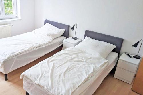 2 letti in una camera con lenzuola e lampade bianche di Chic Apartment with Parking place a Apolda