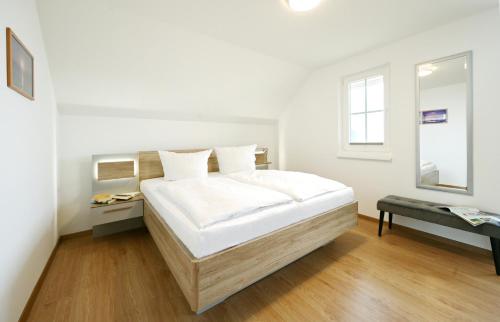 a white bedroom with a bed and a mirror at Ferienwohnung Popeye in Neddesitz