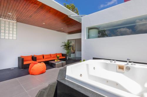 a bathroom with a white tub and an orange couch at Atika Villa Patong in Patong Beach