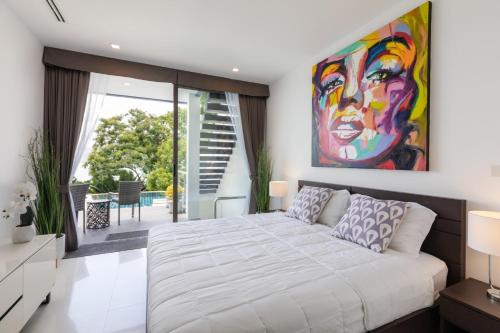 a bedroom with a large bed and a painting on the wall at Atika Villa Patong in Patong Beach