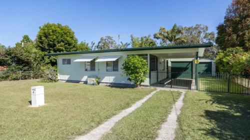 a small house with a fence and a yard at Lowset, pet friendly cottage - Sunset Ave, Bongaree in Bellara