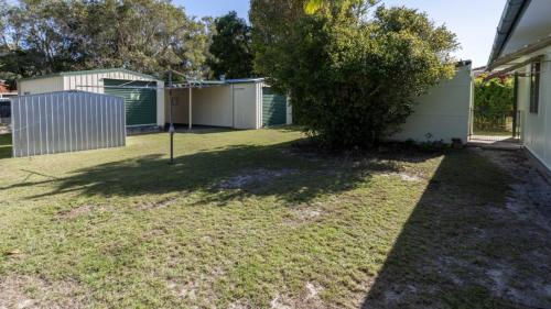 a yard with a tree next to a house at Lowset, pet friendly cottage - Sunset Ave, Bongaree in Bellara