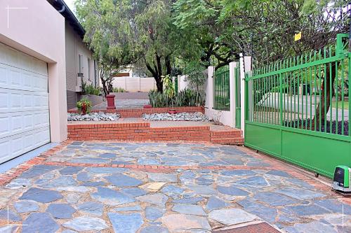 a house with a green gate and a brick patio at THE GLOBAL LINK HUB in Pretoria