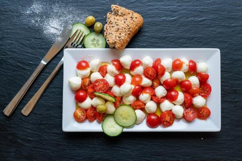 a white plate of food with tomatoes and cucumbers at Das Schreder Hotel in Munich