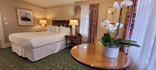 a hotel room with a bed and a table with a vase of flowers at Butterfly Grove Inn in Pacific Grove