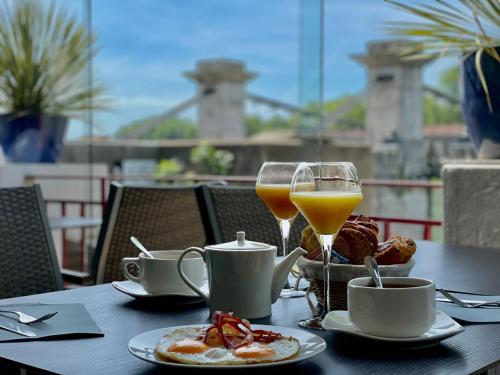 Hôtel Les Deux Coteaux في تين أو هيرميتاج: طاولة مع طعام الإفطار وكأسين من عصير البرتقال