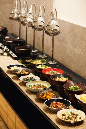 a buffet line with many different bowls of food at hotel MONday Asakusa in Tokyo