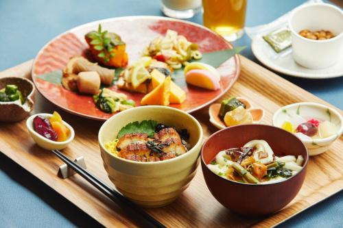 - un plateau en bois avec des bols de nourriture et des assiettes de nourriture dans l'établissement hotel MONday Asakusa, à Tokyo