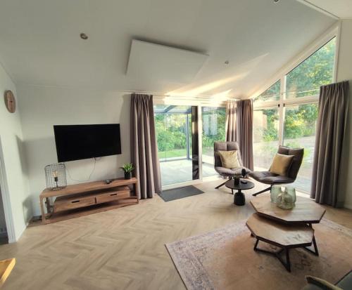 een woonkamer met 2 stoelen en een flatscreen-tv bij Traumhaftes Chalet am Veluwemeer, Bad Hoophuizen in Hulshorst