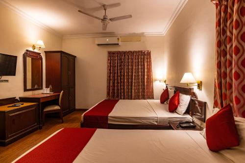 Habitación de hotel con 2 camas y escritorio en Hotel Archana Inn, en Kochi