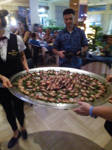 a man holding a large pizza on a pan at Hotel San Francisco Spiaggia in Rimini