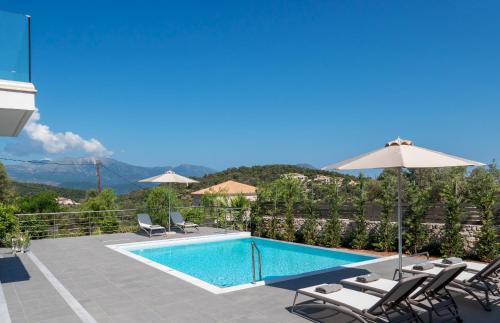 a swimming pool with chairs and an umbrella at Villa Taphian in Meganisi