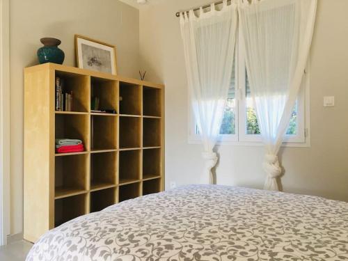 1 dormitorio con cama, estante de libros y ventana en BEROY - Studio entre Forêt et Océan, en Linxe