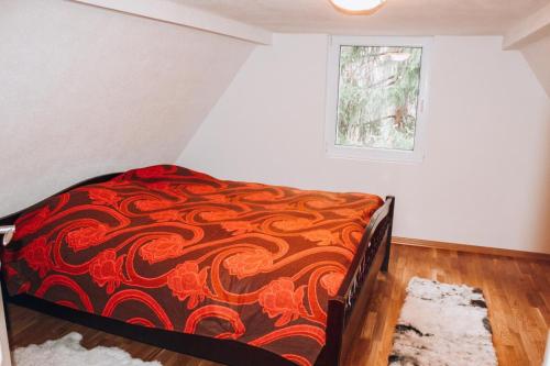 a bedroom with a bed with a red and orange blanket at Villa Katharina in Kakanj