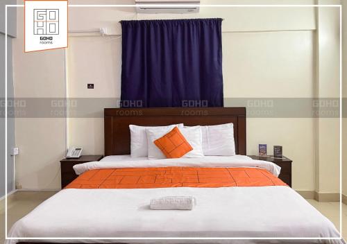 GOHO Rooms 10th Commercial في كراتشي: غرفة نوم بسرير كبير ومخدات برتقالية وبيضاء