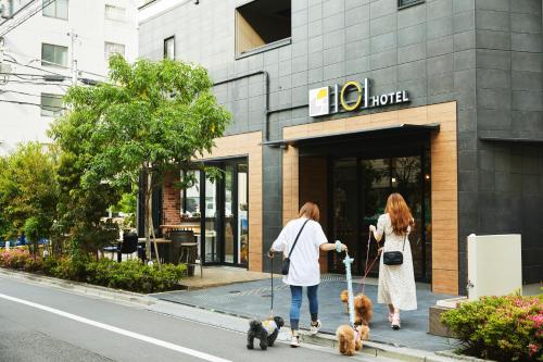 Duas mulheres a passear os cães em frente a uma loja. em ICI HOTEL Asakusabashi em Tóquio