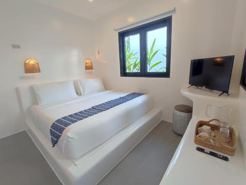 a white bedroom with a bed and a window at Hostel Bajala Siargao in General Luna