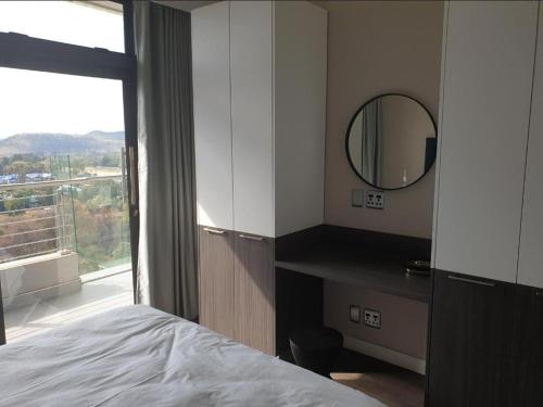 a bedroom with a bed and a mirror and a window at Menlyn Maine Apartments in Pretoria