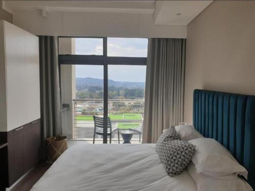 a bedroom with a bed and a large window at Menlyn Maine Apartments in Pretoria